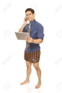 GUy wearing dress shirt, tie, and boxers, holding lap top and talking on the phone.